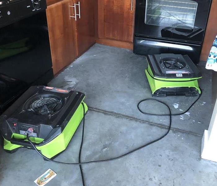 Kitchen floor with two green air movers. 