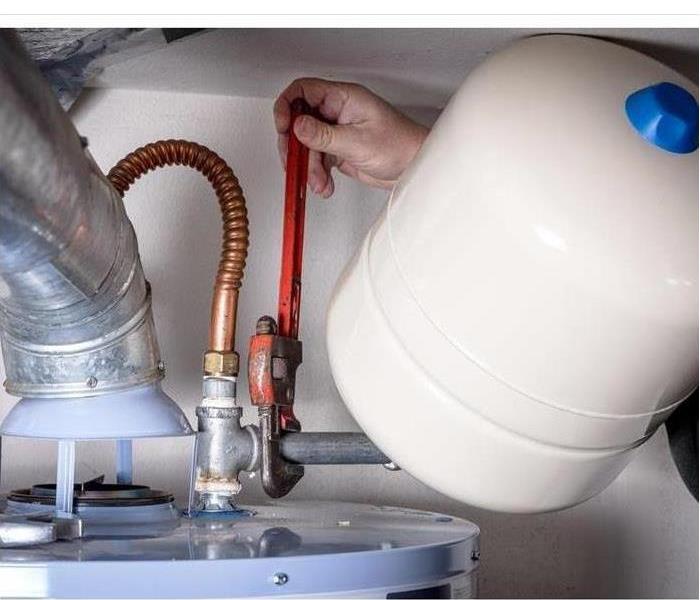 Plumber installs a compression tank on a hot water heater.